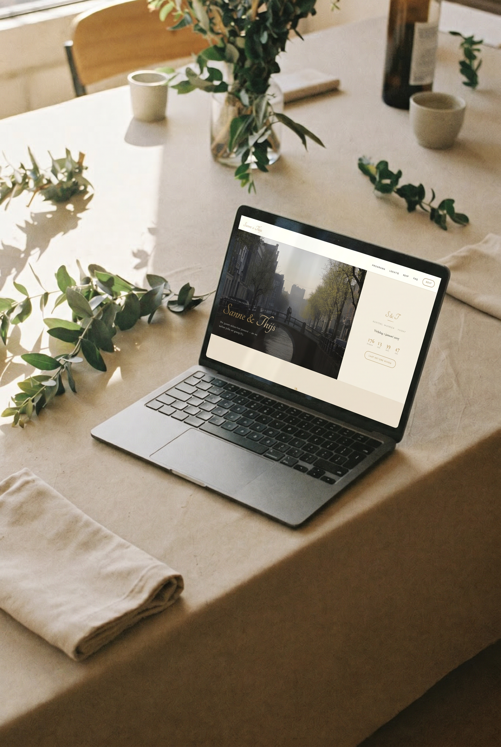 Laptop op een linnen tafel in zacht ochtendlicht, met een trouwwebsite op maat op het scherm